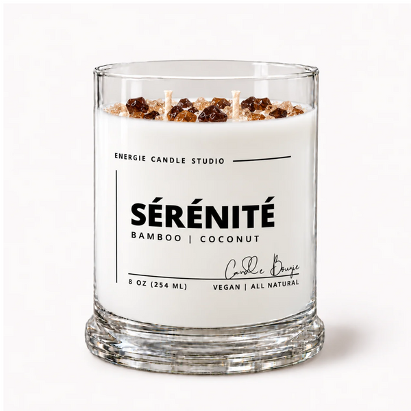 A glass jar candle with white wax and three wicks, topped with brown and beige decorative elements. The clear glass jar has a white label reading 'ENERGIE CANDLE STUDIO SÉRÉNITÉ BAMBOO | COCONUT' on a clean white background.