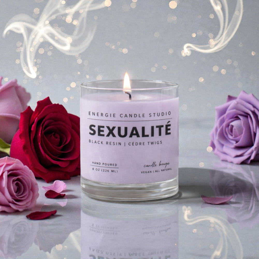 Candle labeled 'Sexualite' with roses on a reflective surface and light background