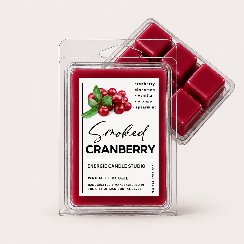Two clear plastic clamshell packages of Energize Candle Studio Smoked Cranberry wax melts on a light warm gray background. The front package shows a white label with red cranberry graphics and text, while the rear package shows several deep cranberry wax cubes inside a clear tray.