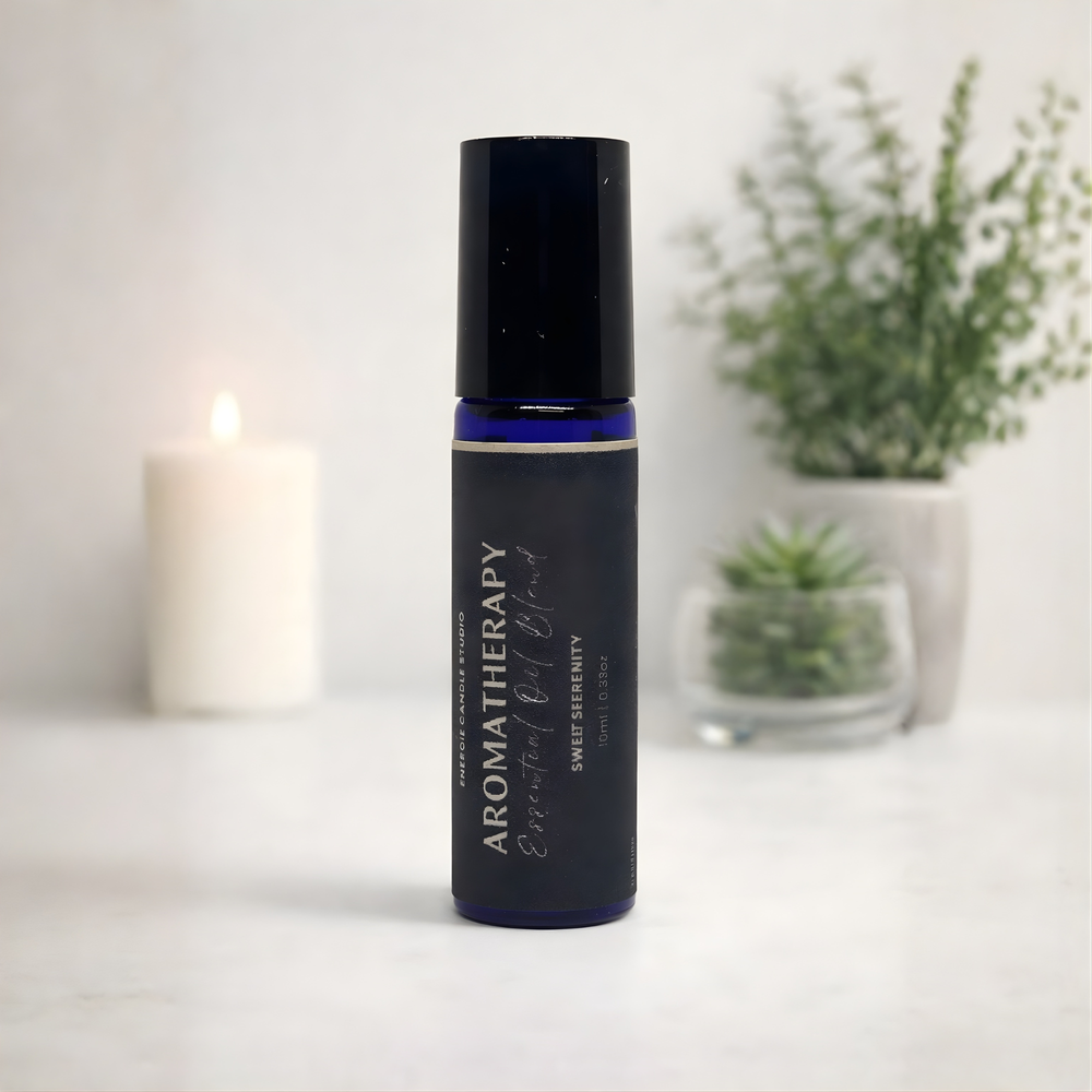 Aromatherapy essential oil roller bottle on a white surface with a candle and plants in the background.