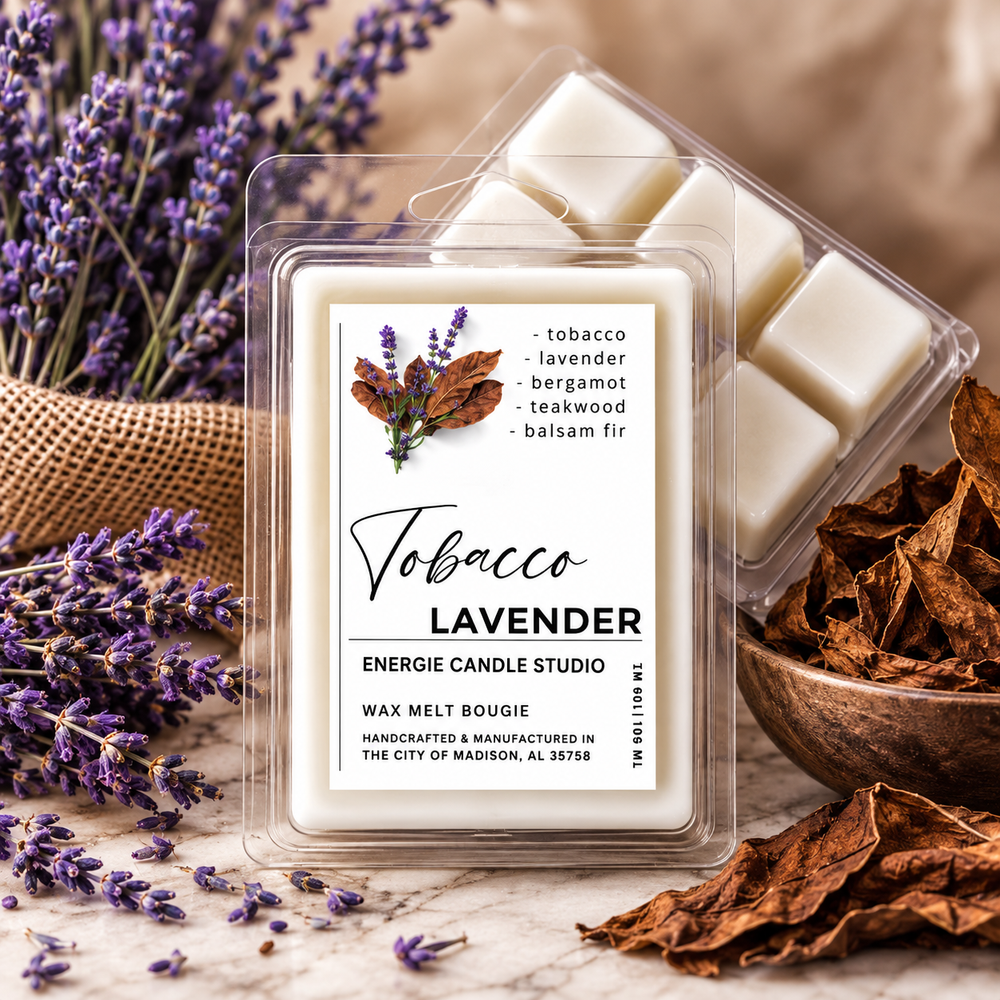 A packaged wax melt candle labeled Tobacco Lavender sits on a stone surface with lavender sprigs, dried leaves, and a burlap sack in the background. The clear plastic clamshell shows several off-white wax pieces, and the front label includes the brand name Energie Candle Studio and scent notes of tobacco, lavender, bergamot, teakwood, and balsam fir.