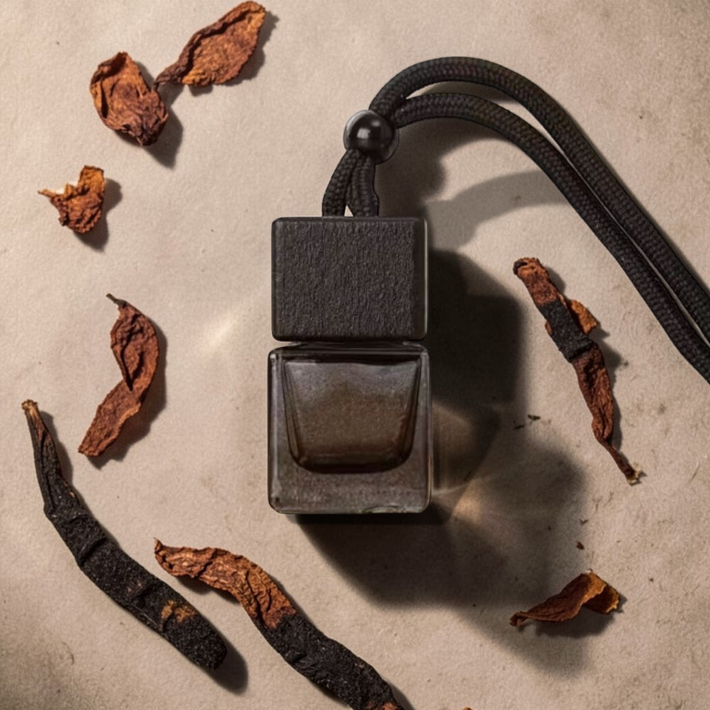 Dark metal pendant with a cord on a textured surface with dried leaves