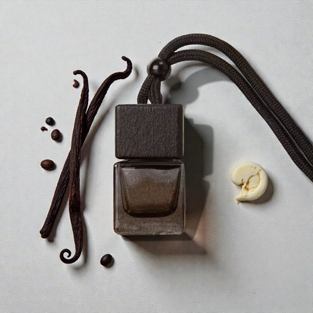 Perfume bottle with vanilla beans, coffee beans, and a vanilla pod on a light background