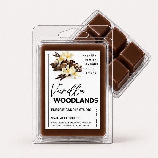 Two clear plastic clamshell wax melt packages on a clean white background. The front package is labeled 'Vanilla Woodlands' by Energie Candle Studio and contains dark brown wax cubes.