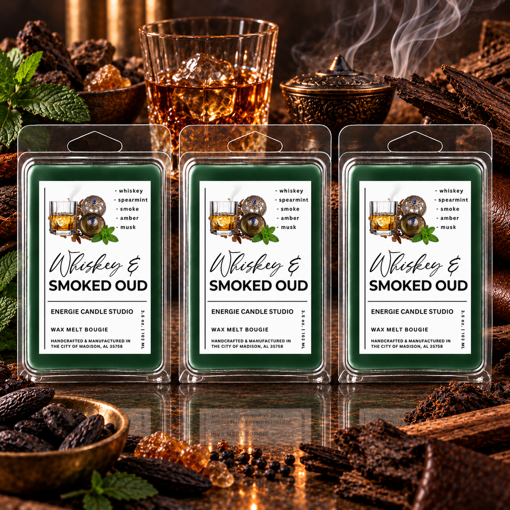 Three packaged wax melts labeled 'Whiskey & Smoked Oud' are displayed in front of a warm, rustic background with whiskey glasses, wood, and spices. The wax melts are in clear plastic clamshell packaging with green labels featuring white text and an illustration of a whiskey glass with ice and spices.